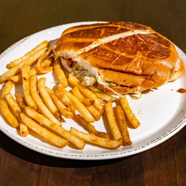 A large Mexican torta sandwich, cut in half, served with a side of golden french fries.