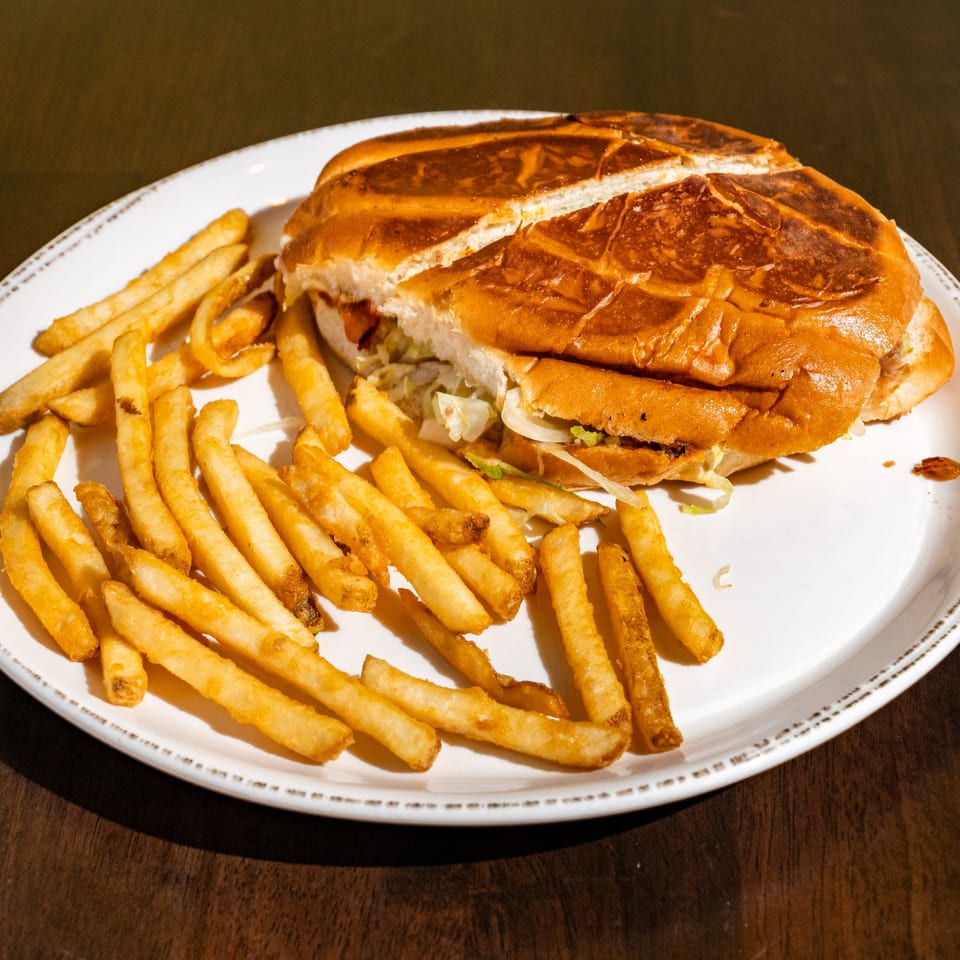 A large Mexican torta sandwich, cut in half, served with a side of golden french fries.