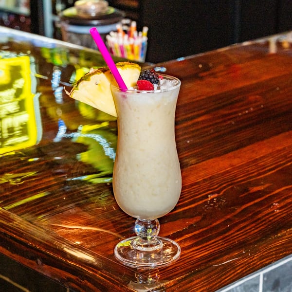 A Chuyita's Mexican Restaurant piña colada with pineapple, raspberry, and blackberry garnish on a bar.